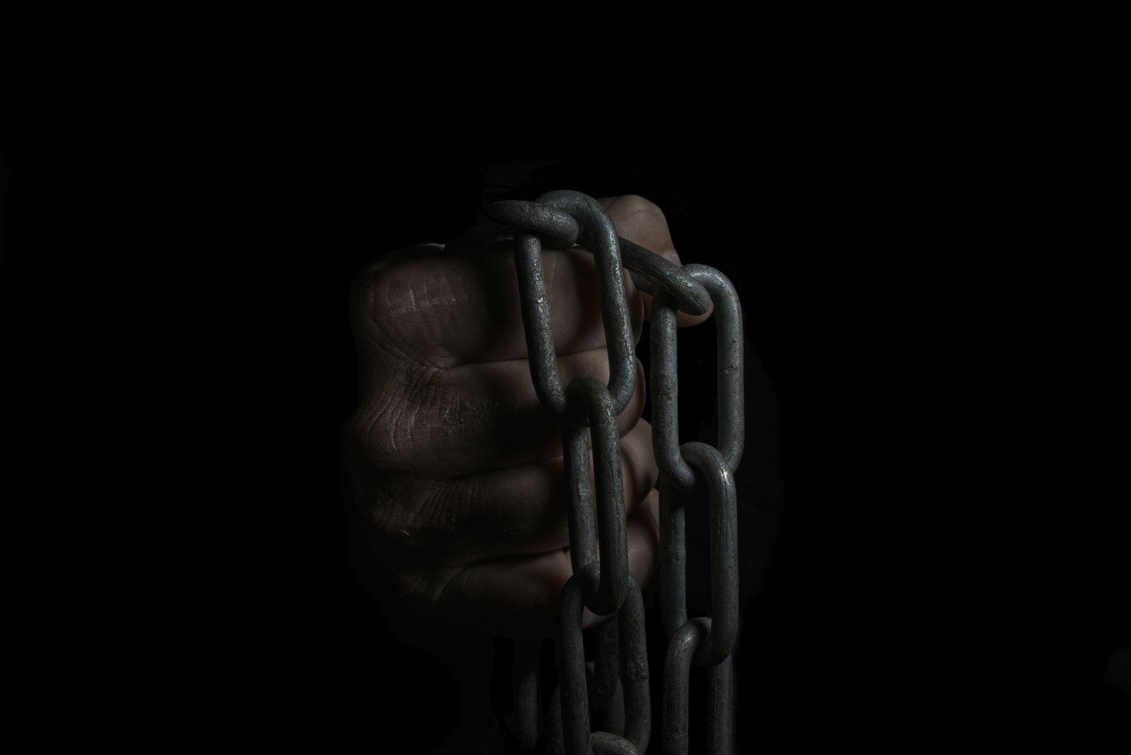 A hand holding a chain in the dark